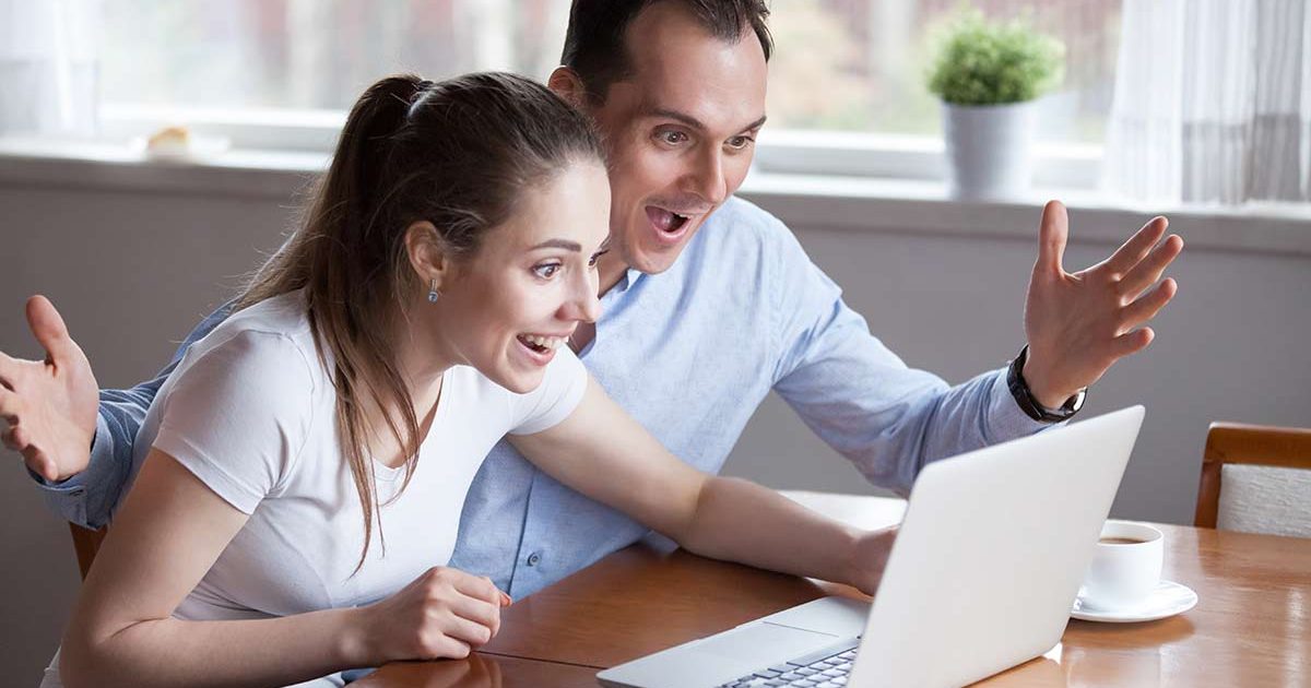 excited couple looking at a laptop